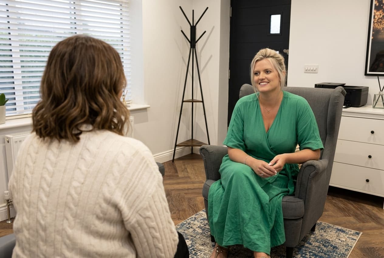 Katherine Richmond in session with a client, seated in warm-grey armchairs in her Horsforth therapy room